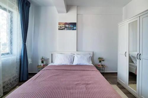 a bedroom with a large bed with a red blanket at By the Sea Plusoi Apartment in Năvodari