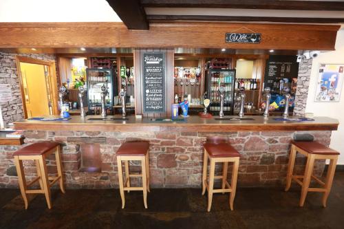 a bar with three stools and a brick wall at Lyons Manor House Caravan Park in Mawbray