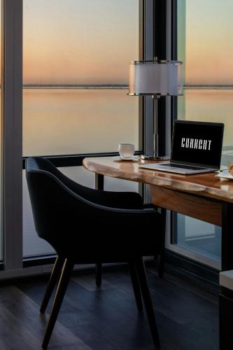 a desk with a laptop and a chair next to a window at The CURRENT Hotel, Autograph Collection in Tampa
