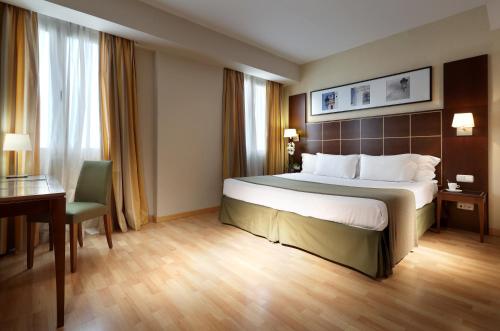 a hotel room with a large bed and a desk at Exe Tartessos in Huelva