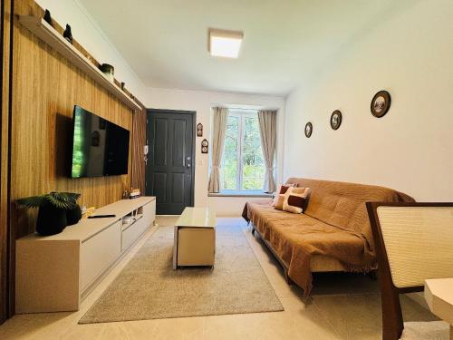 ein Schlafzimmer mit einem Bett, einem Fernseher und einer Couch in der Unterkunft MRG - Convidativa Casa 3D em Condomínio Privativo em Canela - Próximo ao Parque Terra Mágica Florybal in Canela