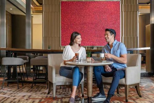 a man and woman sitting at a table in a restaurant at Sheraton Manila Hotel at Newport World Resorts in Manila
