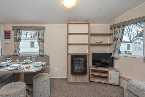 a living room with a table and a tv at Lyons Manor House Caravan Park in Mawbray