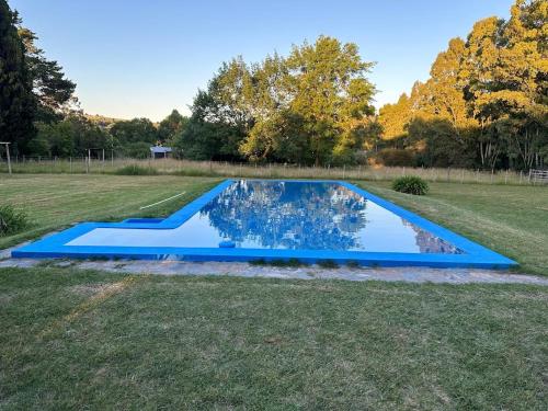 a blue pool in the middle of a grass field at Las Marias in Tandil