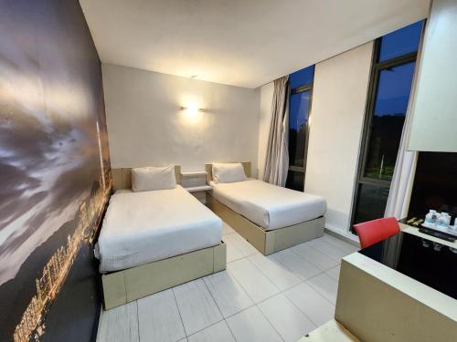 a hotel room with two beds and a flat screen tv at Kozi Hotel - Danga Bay in Johor Bahru