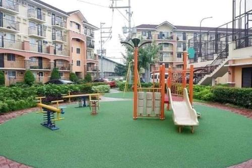 a playground with play equipment on a green field at Cozy 1 Bedroom Unit Arezzo Place Pasig in Pasig