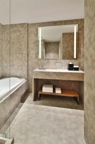 a bathroom with a sink and a tub and a mirror at Courtyard by Marriott Nashik in Nashik