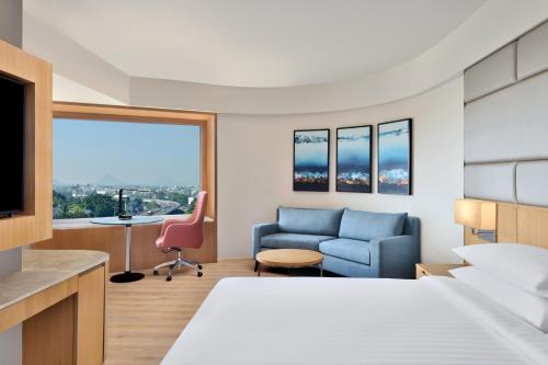 a hotel room with a bed and a desk and a chair at Courtyard by Marriott Nashik in Nashik