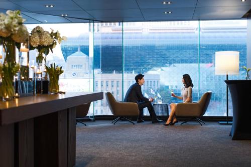 a man and woman sitting in chairs in a lobby at THE PLAZA Seoul, Autograph Collection in Seoul