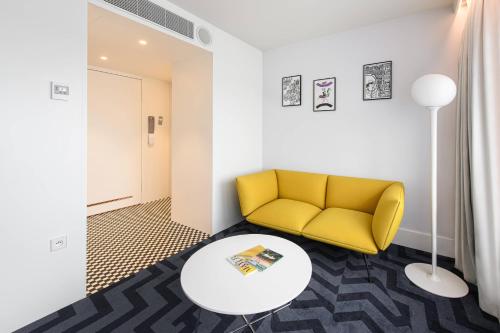 a living room with a yellow couch and a table at Renaissance Warsaw Airport Hotel in Warsaw