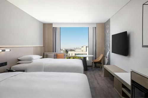 a hotel room with two beds and a television at AC Hotel by Marriott Suzhou, Guan Qian in Suzhou