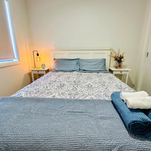 a bedroom with a bed and two tables with towels at Cozy Homez Ballarat - Home stay in Alfredton