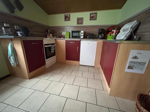a kitchen with red and white cabinets and appliances at Ferienhaus Zittau Oberlausitz & Ferienwohnung am Hamann Berg in Zittau