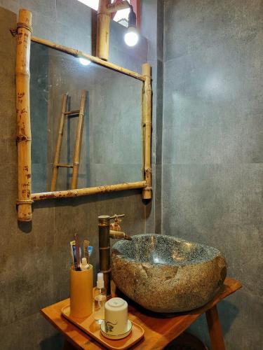 a bathroom with a stone sink on a wooden table at Nông Trại Thảnh Thơi in Ben Tre