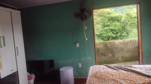 a bedroom with a green wall and a window at Casa Branca Sobrado in Caraguatatuba