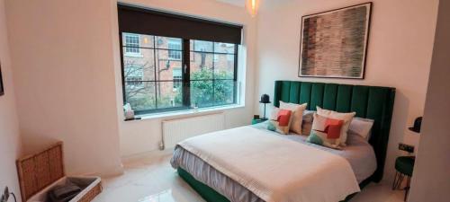 チェスターにあるLuxury Apartment: city centre, stylish, modernのベッドルーム1室(緑のヘッドボードと窓付)