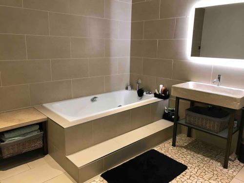 une salle de bain avec une baignoire et un lavabo dans l'établissement Maison de village toute équipée, à Arnaville