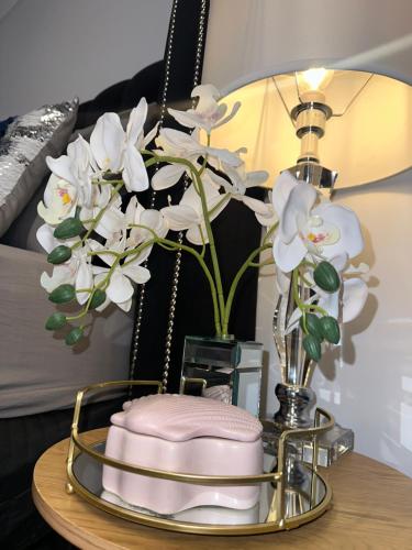 a table with a lamp and a vase with white flowers at Devonport Breeze Escape in Devonport