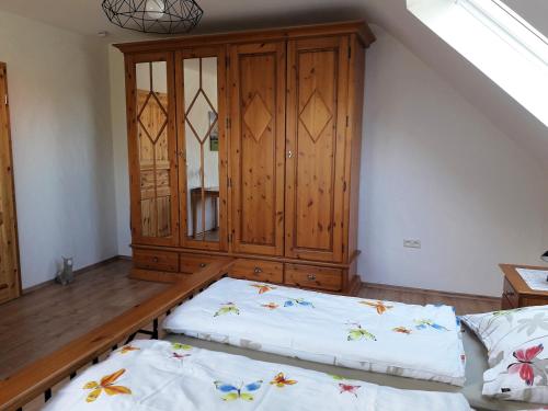 a room with two beds and a wooden cabinet at Landhaus Grimburg - Ferienwohnung Obergeschoss in Grimburg
