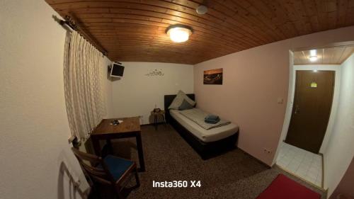 a small room with a bed and a table and a door at Gästehaus Eulenköpfchen in Neef