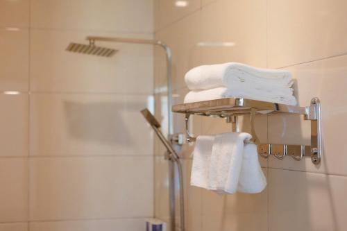 a bathroom with a shower and towels on a rack at NOI BAI AIRPORT Hotel-内排华星酒店 in Hanoi