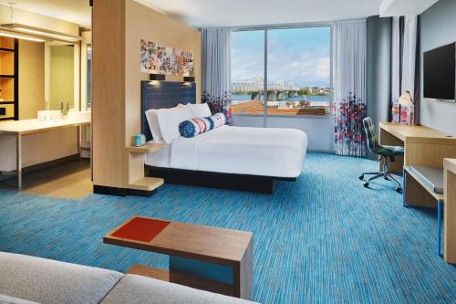 a hotel room with a bed and a desk at Aloft Louisville Downtown in Louisville