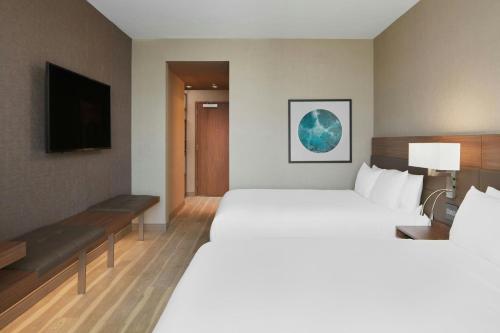 a hotel room with a large bed and a television at AC Hotel by Marriott Reston in Reston