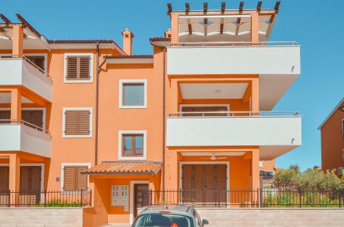 an orange building with a car parked in front at Apartment Dertil Premantura in Premantura