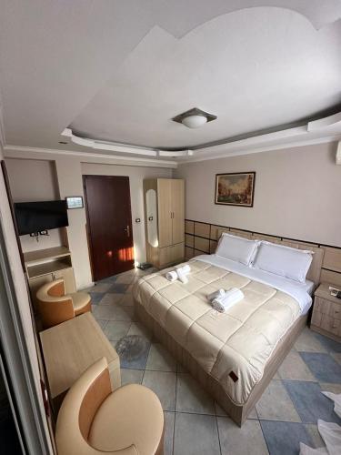 a bedroom with a large bed and a chair at Hotel Ideal in Shkodër