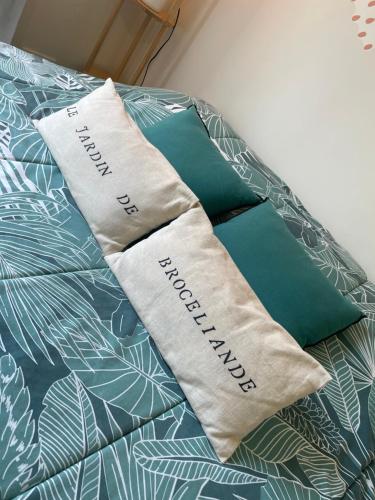a bed with two pillows on top of it at Le jardin de Broceliande in Ploërmel