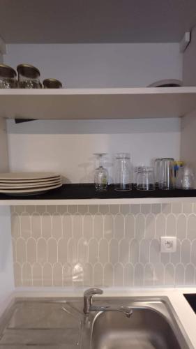 a kitchen with a sink and a shelf with dishes at Your Ardennes Adventure - Studio in Jalhay