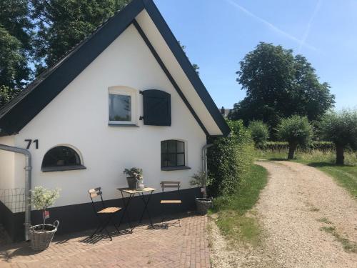 a white house with a table and chairs next to a dirt road at B&B De Jagthut in Driel