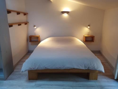 a white bed in a room with two lights at Les Studios de St Guilhem in Saint-Guilhem-le-Désert