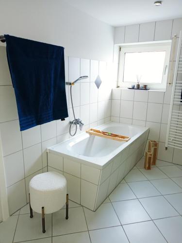 a white bathroom with a tub and a chair at Ferienwohnung am Wald in Warstein