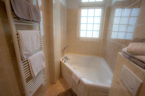 La salle de bains est pourvue d'une baignoire et d'une fenêtre. dans l'établissement Villa Augeval Hôtel de charme & Spa, à Deauville
