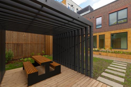 a black pergola with a wooden bench on a deck at Revalia Lastekodu-Odra Bus Station Airport Apartments in Tallinn