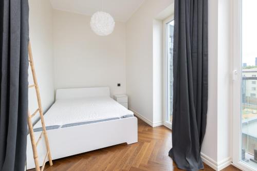 a white bedroom with a bed and a window at Revalia Lastekodu-Odra Bus Station Airport Apartments in Tallinn