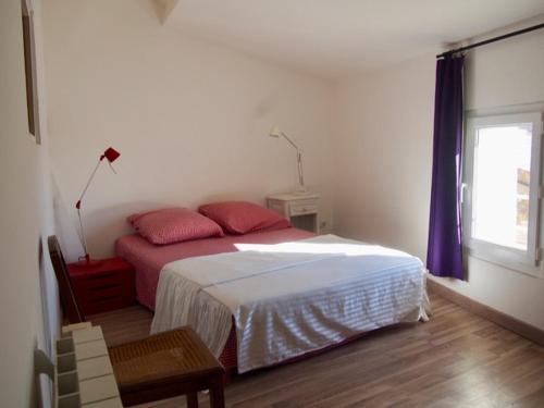 une chambre avec un lit avec des oreillers rouges et une fenêtre dans l'établissement Place du village Haute Provence, à Puimichel