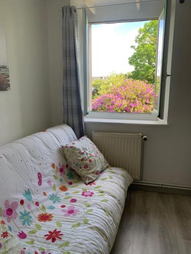 - un lit avec un oreiller et une fenêtre fleurie dans l'établissement Grande maison au cœur du pays bigouden, à Plonéour-Lanvern