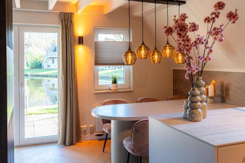 a kitchen and dining room with a table and chairs at Casa Vida Verde - Luxe vakantiewoning aan het water! in Gramsbergen