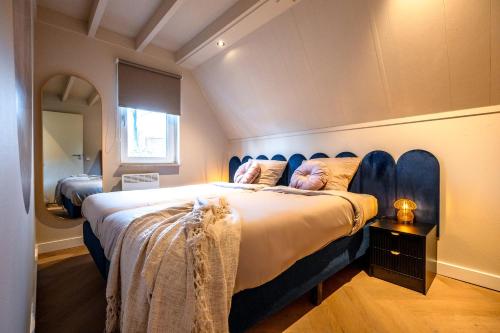 a bedroom with a large bed with a blue headboard at Casa Vida Verde - Luxe vakantiewoning aan het water! in Gramsbergen