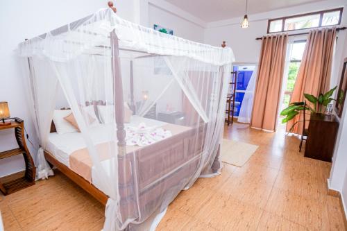 a bedroom with a bed with a canopy at Nibbana Mirissa Hotel in Mirissa
