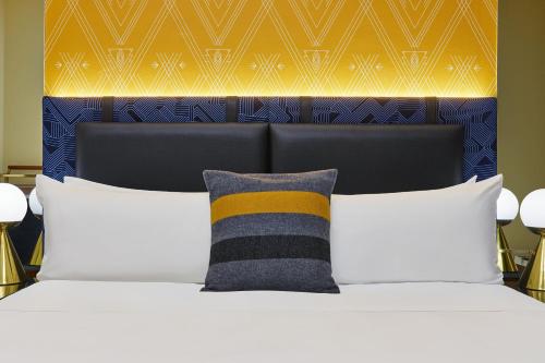 a bed with white pillows and a yellow and blue headboard at W Minneapolis - The Foshay in Minneapolis