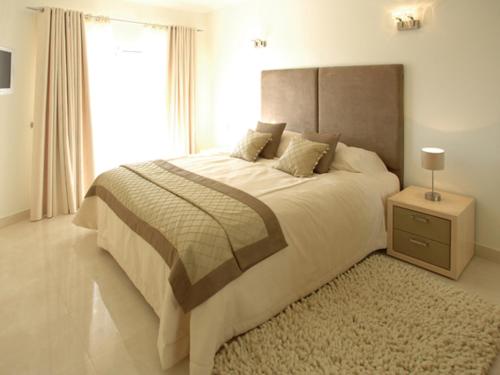 
a neatly made bed in a hotel room at Quinta da Floresta – Santo António Villas, Golf & Spa in Budens
