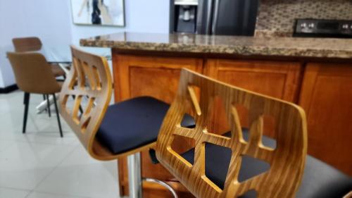 two chairs sitting at a counter in a kitchen at Luxury 2-Bedroom Suite adjacent AC Marriott Hotel New Kingston in Kingston
