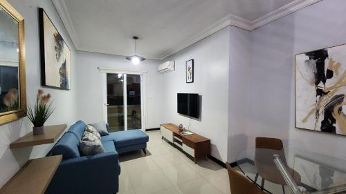 a living room with a blue couch and a tv at Luxury 2-Bedroom Suite adjacent AC Marriott Hotel New Kingston in Kingston