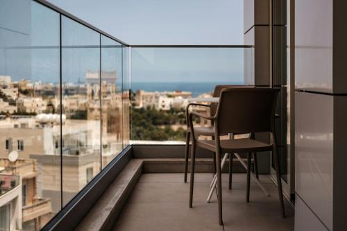 a table and chairs on a balcony with a view at AC Hotel by Marriott St Julian's in St Julian's