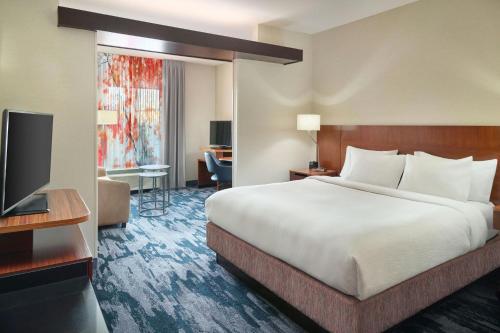 a hotel room with a bed and a flat screen tv at Fairfield Inn & Suites by Marriott Jackson in Jackson