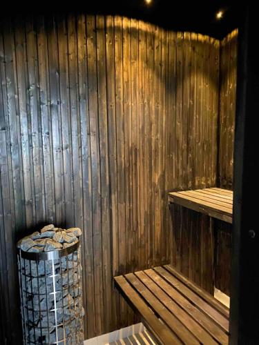 a sauna with a trash can and a wooden wall at Delicious pool villa near Tylösand in Halmstad