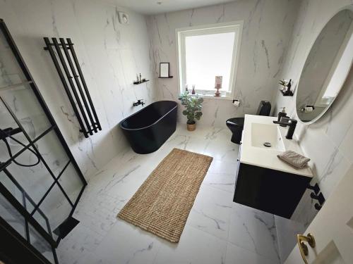 a bathroom with a black tub and a sink and a mirror at Delicious pool villa near Tylösand in Halmstad
